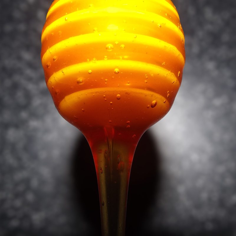 Golden Manuka honey dripping from a dipper